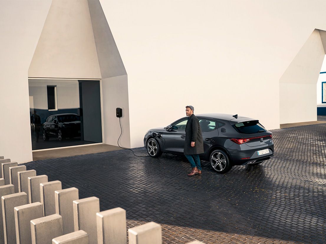 Ein Mann lädt gerade seinen SEAT Leon 5-Türer und geht daneben