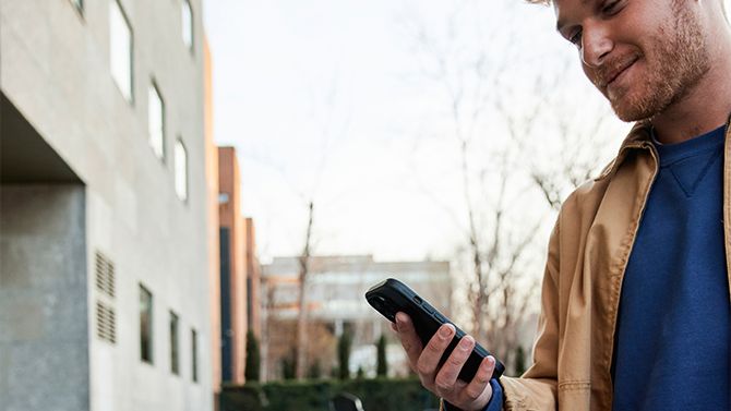 Ein Mann mit einem Smartphone in der Hand steht vor einem SEAT MÓ 50