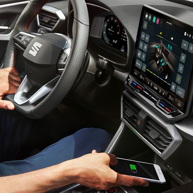 Mann nutzt das Wireless Charging des SEAT Leon, um sein Smartphone aufzuladen
