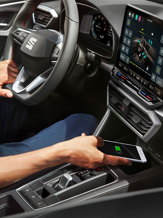 Mann nutzt das Wireless Charging des SEAT Leon, um sein Smartphone aufzuladen