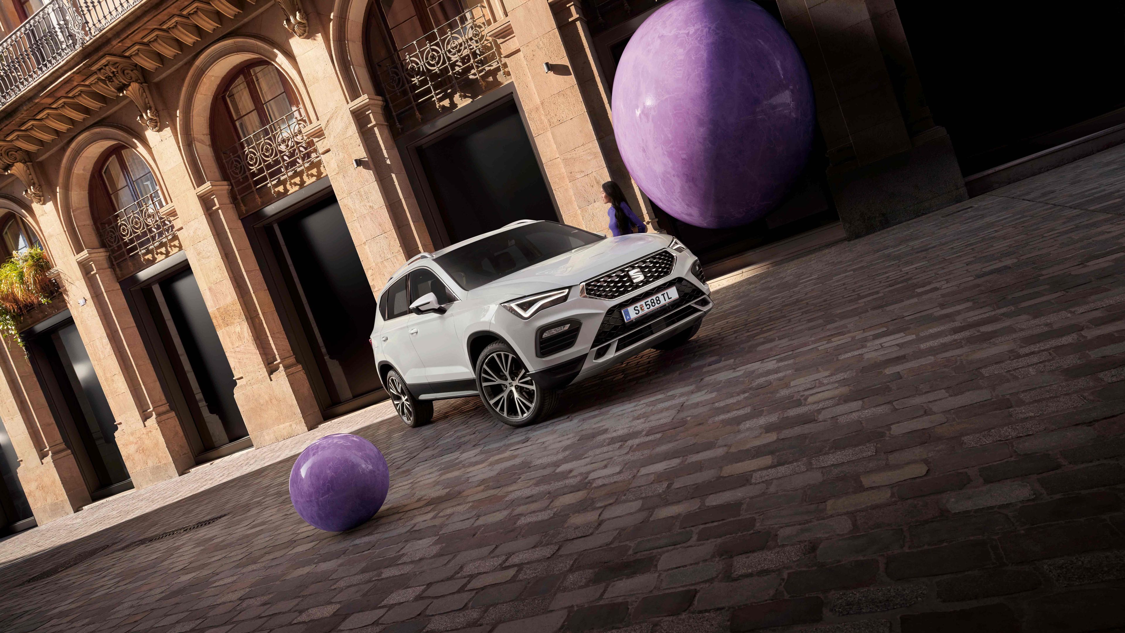 Ein weißer SEAT Ateca  steht perspektivisch aufgenommen vor einem älteren aber eleganten Gebäude