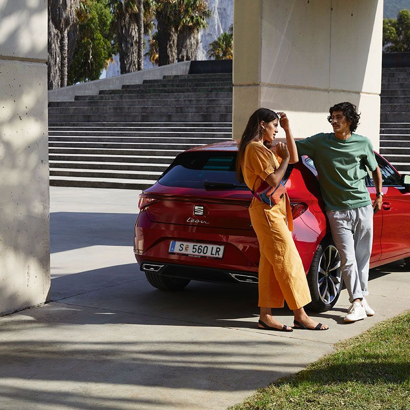 Casal deitado junto ao SEAT Leon vermelho desire 