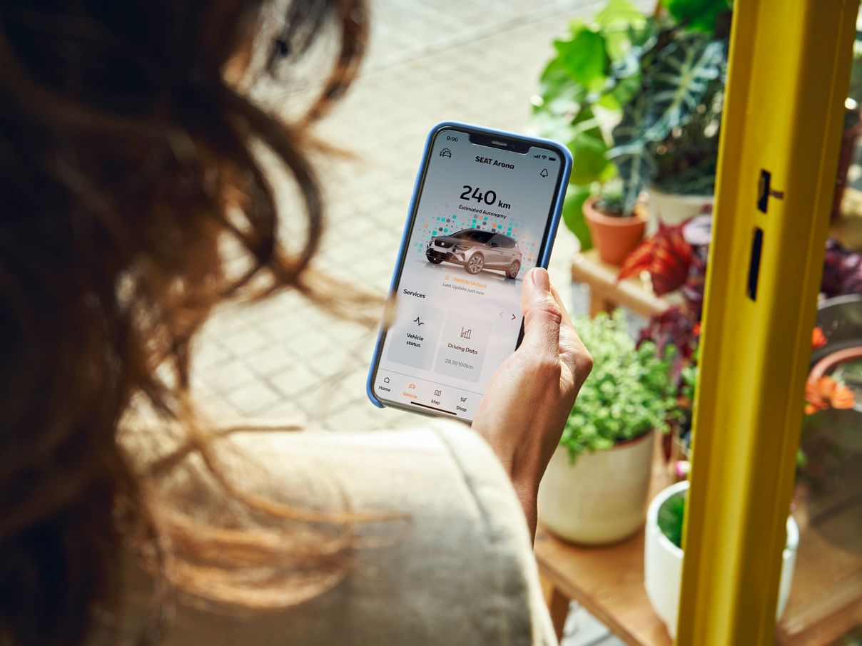 Eine Frau hält ihr Smartphone in der Hand und nutzt gerade SEAT Connect