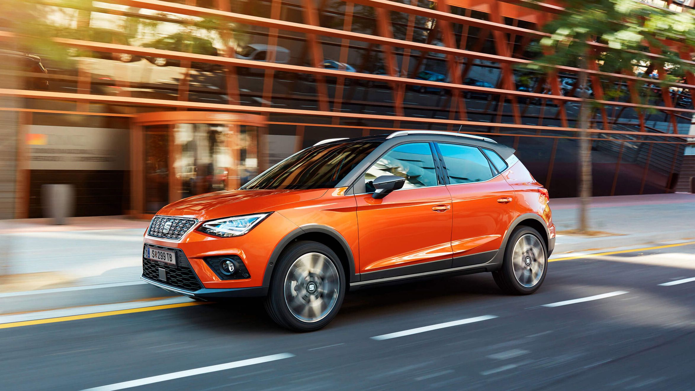 Ein SEAT Arona in auffälligem Orange fährt dynamisch die Straße entlang