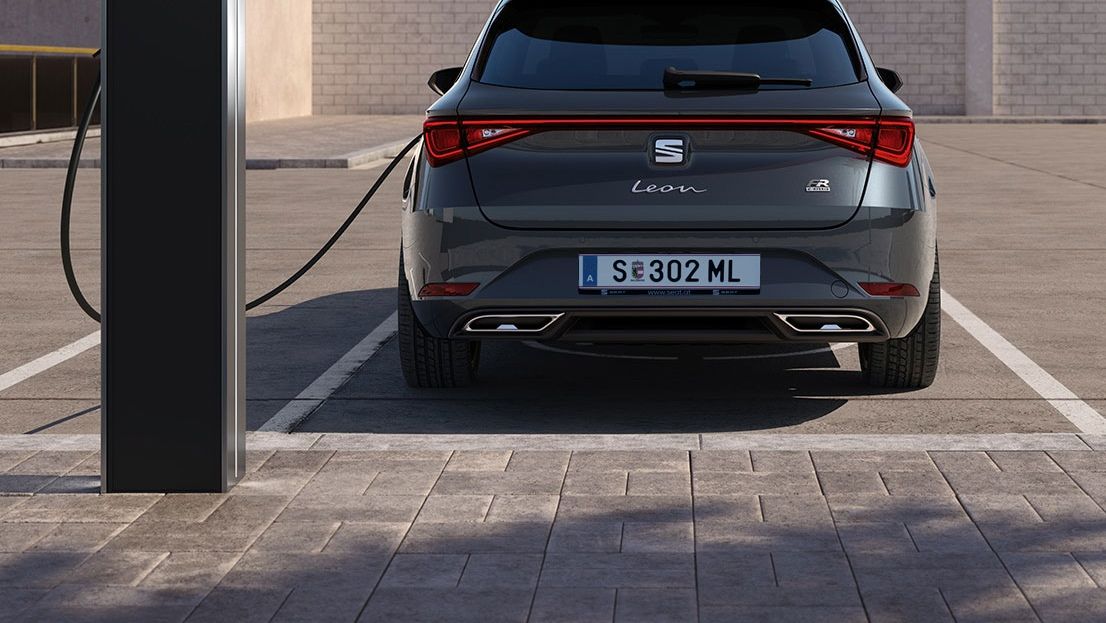 Der SEAT Leon Hybrid in elegantem Magnetic Tech ist an eine E-Ladestation angeschlossen