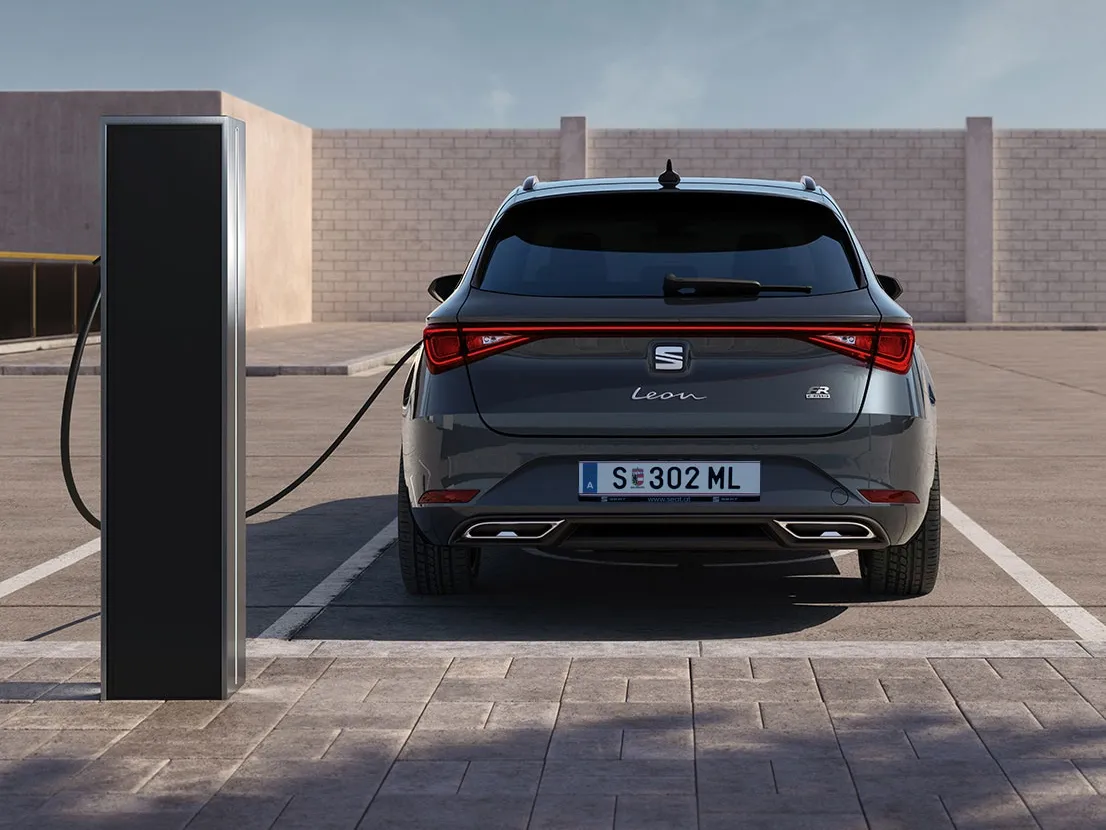 Der SEAT Leon Hybrid in elegantem Magnetic Tech ist an eine E-Ladestation angeschlossen