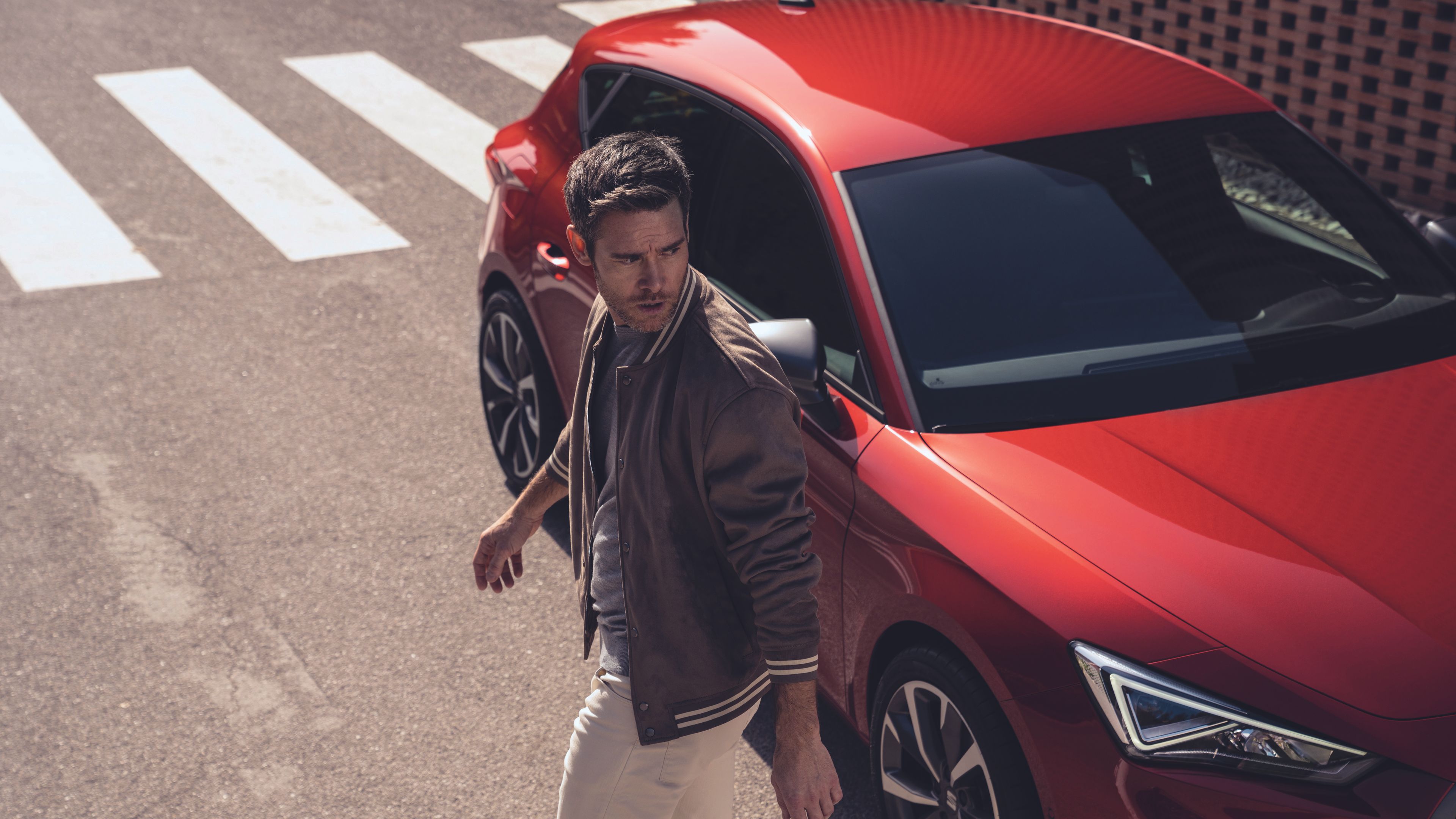Mann geht von einem roten SEAT Leon weg 
