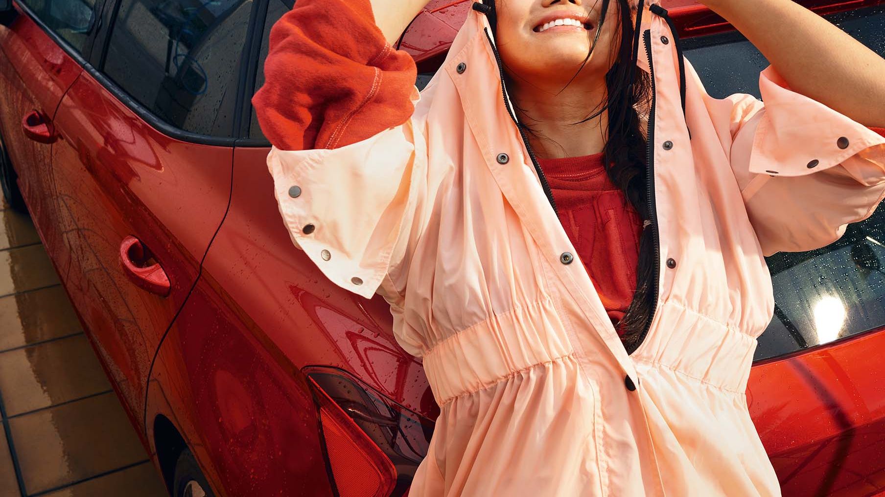 Eine lächelnde Frau lehnt an einem roten SEAT Ibiza