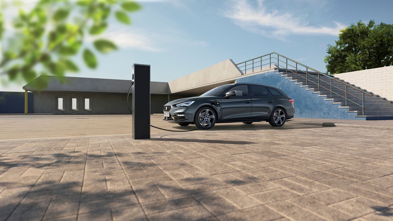 Ein grauer SEAT Leon SP Kombi steht an der Ladesäule mit Ladekabel verbunden.
