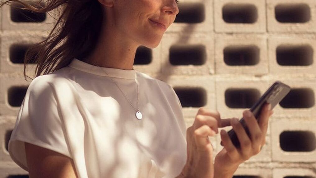Eine Frau hält ihr Smartphone in der Hand und nutzt gerade SEAT Connect