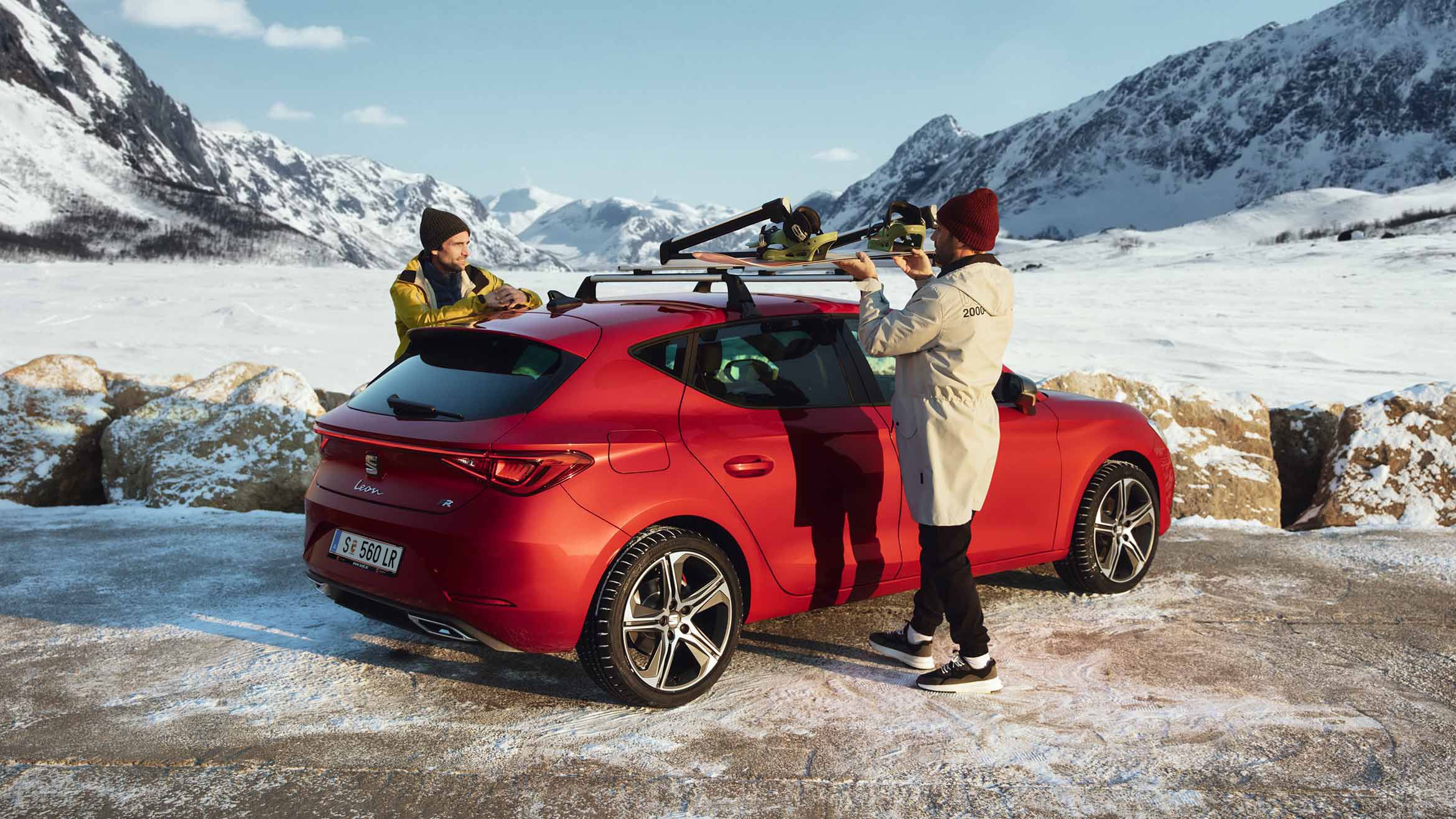 Freunde befestigen einen Skiträger an einem SEAT Leon in Desire Red