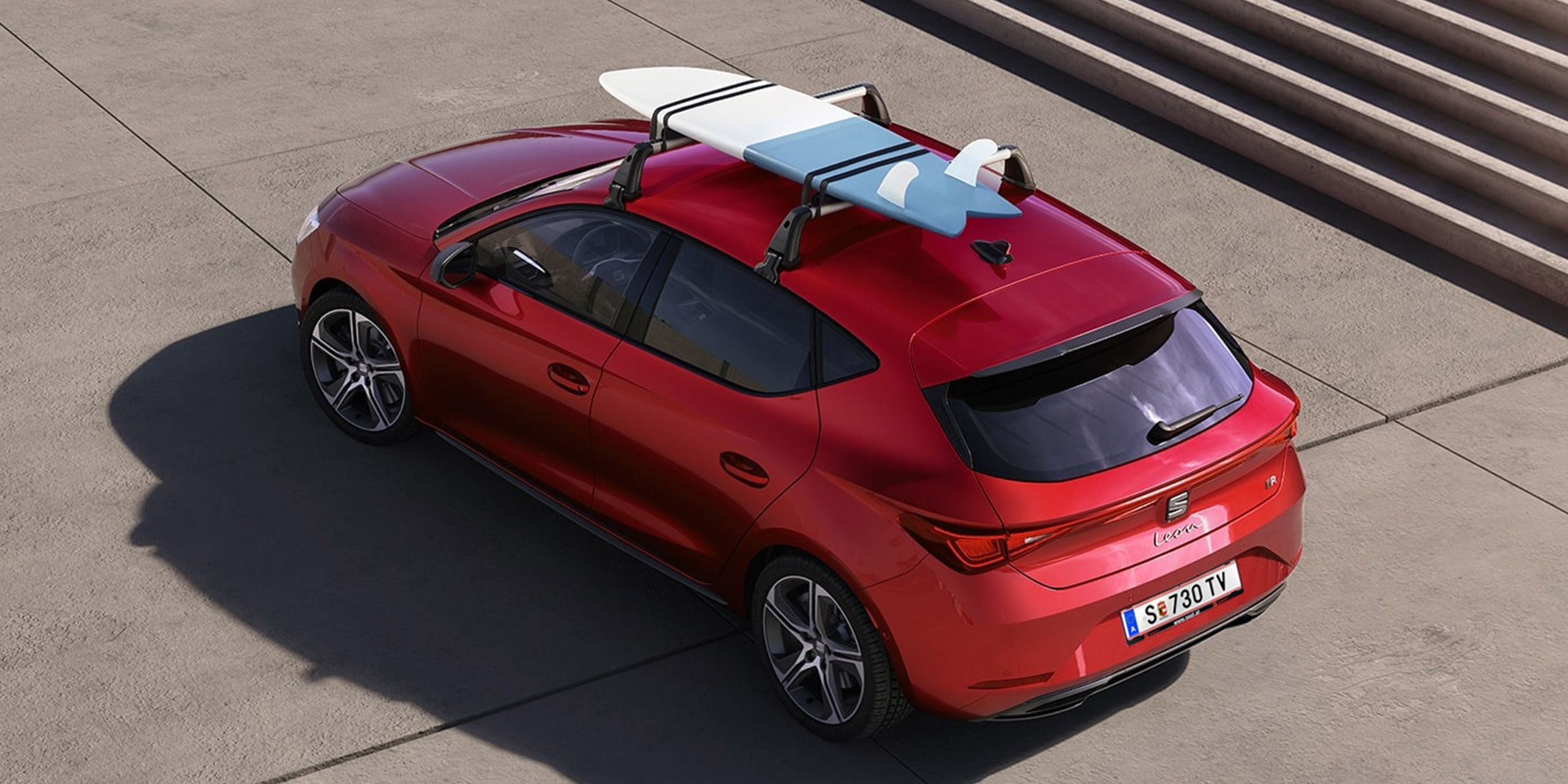 Ein SEAT Leon mit montierten Dachträgern, auf denen ein Surfbrett befestigt ist
