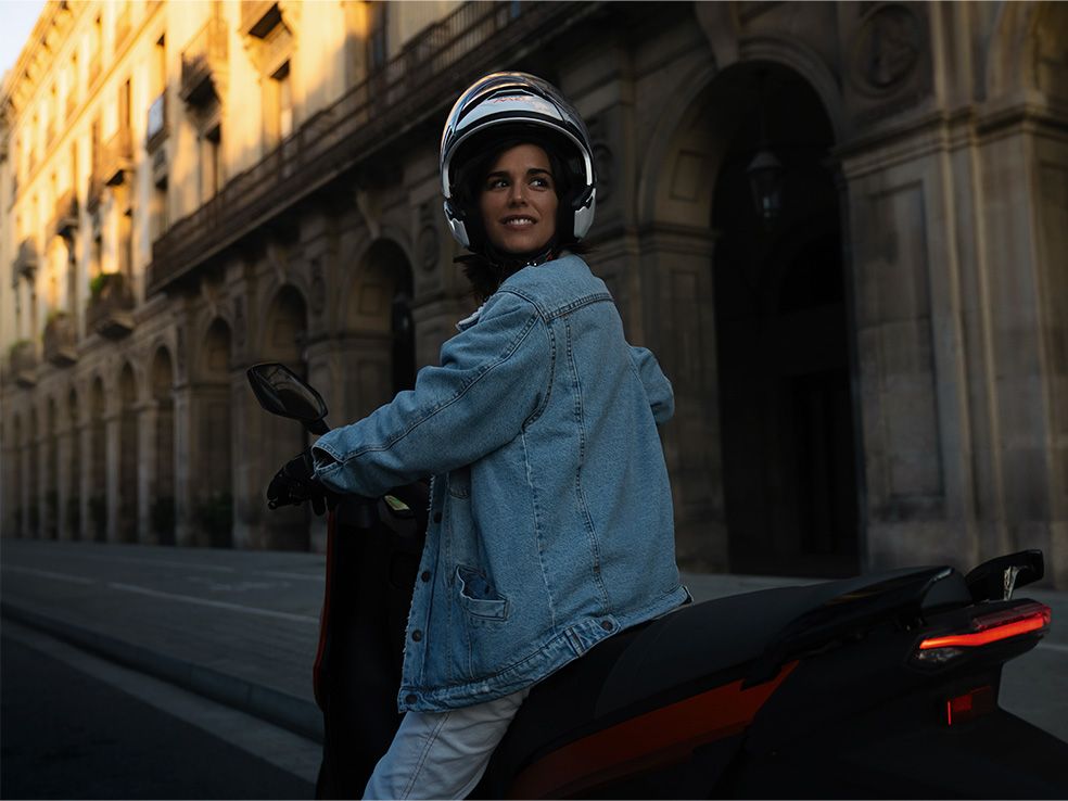 mulher conduz a sua scooter elétrica SEAT MÓ 125 com uma velocidade máxima de 95 km/h