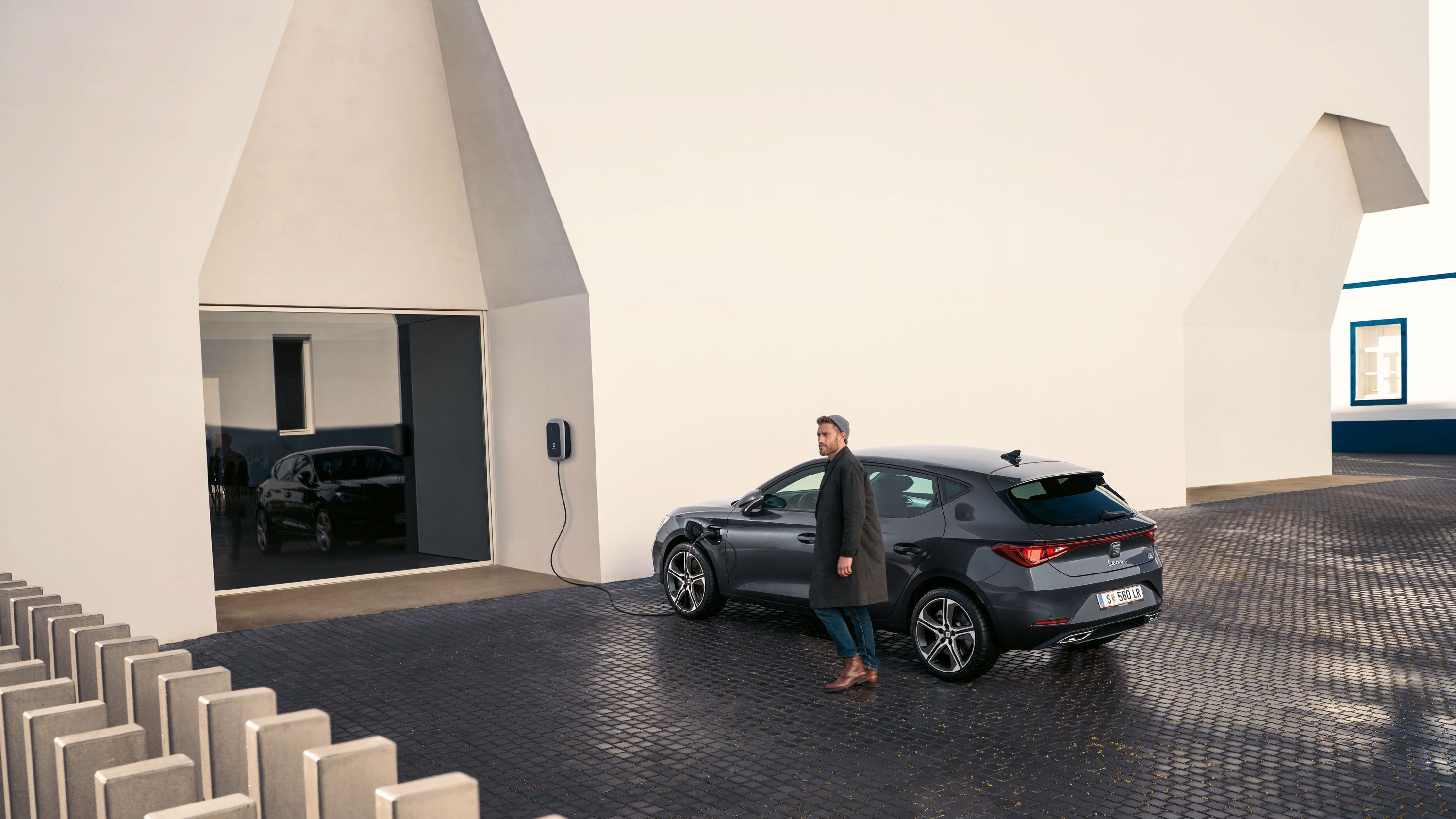 Ein Mann lädt seinen SEAT Leon Hybrid und geht zum Auto 