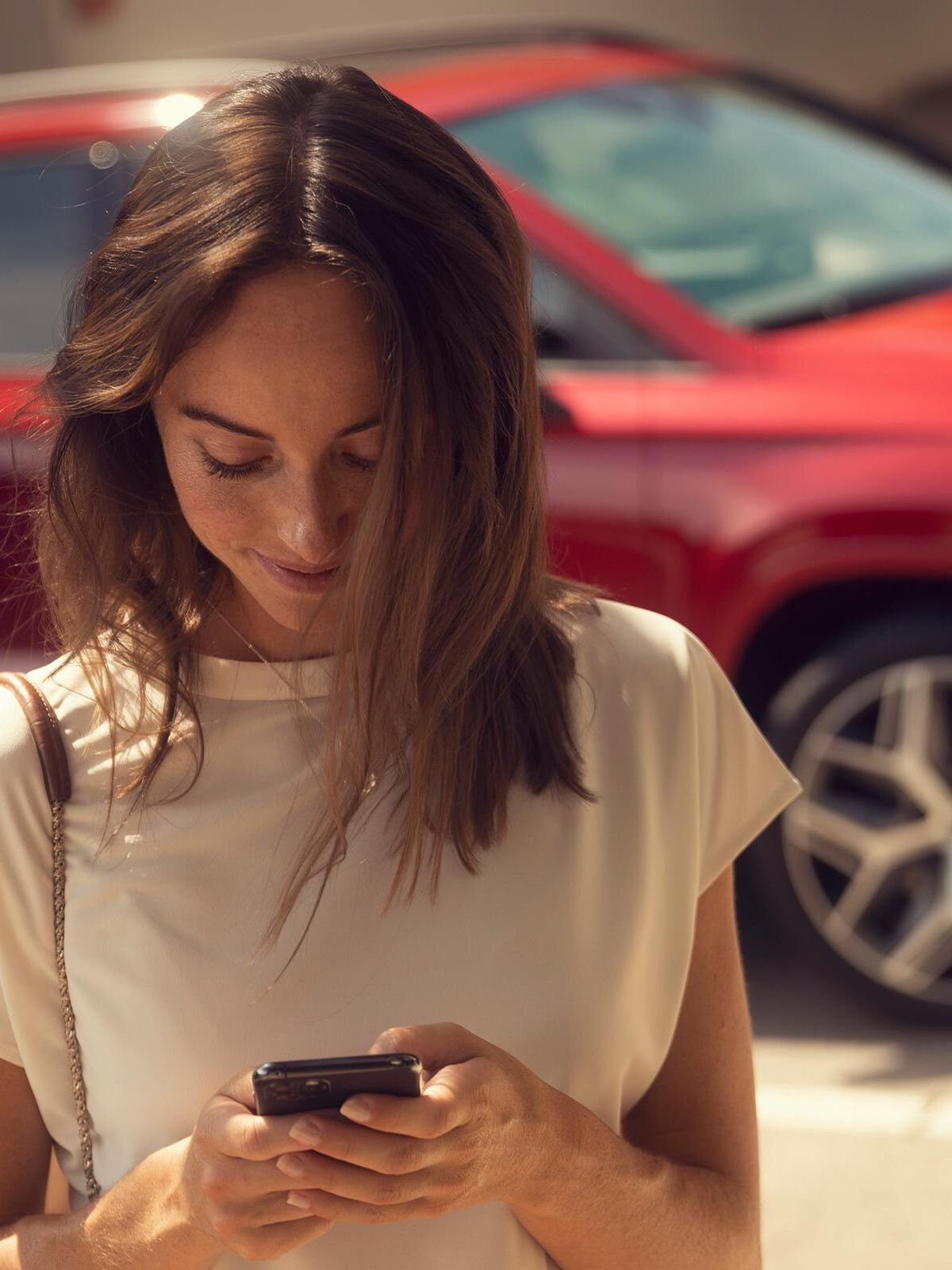 Eine Frau hält ihr Smartphone in der Hand und nutzt gerade SEAT Connect