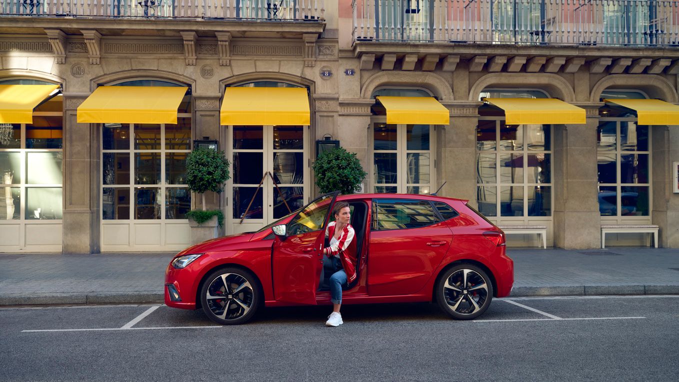 Eine Frau steigt aus einem geparkten, roten SEAT Ibiza aus