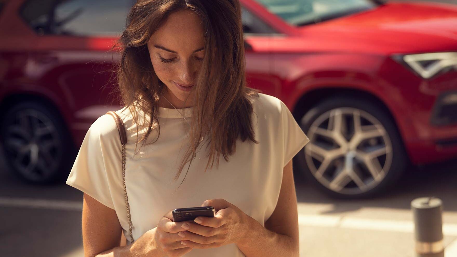 Eine Frau hält ihr Smartphone in der Hand und nutzt gerade SEAT Connect
