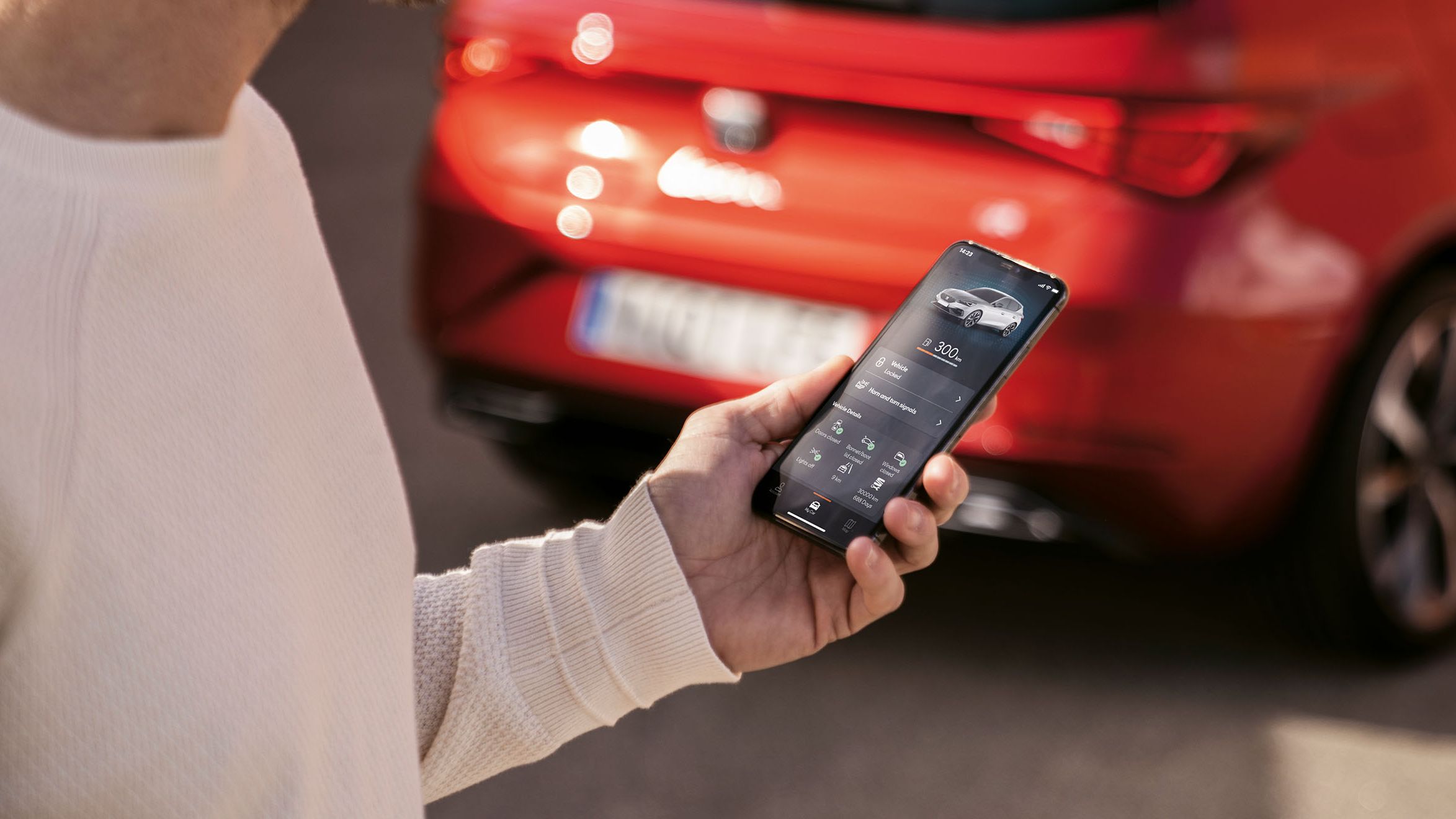 Ein Mann ruft über eine App die aktuelle Reichweite seines roten SEAT Leon ab