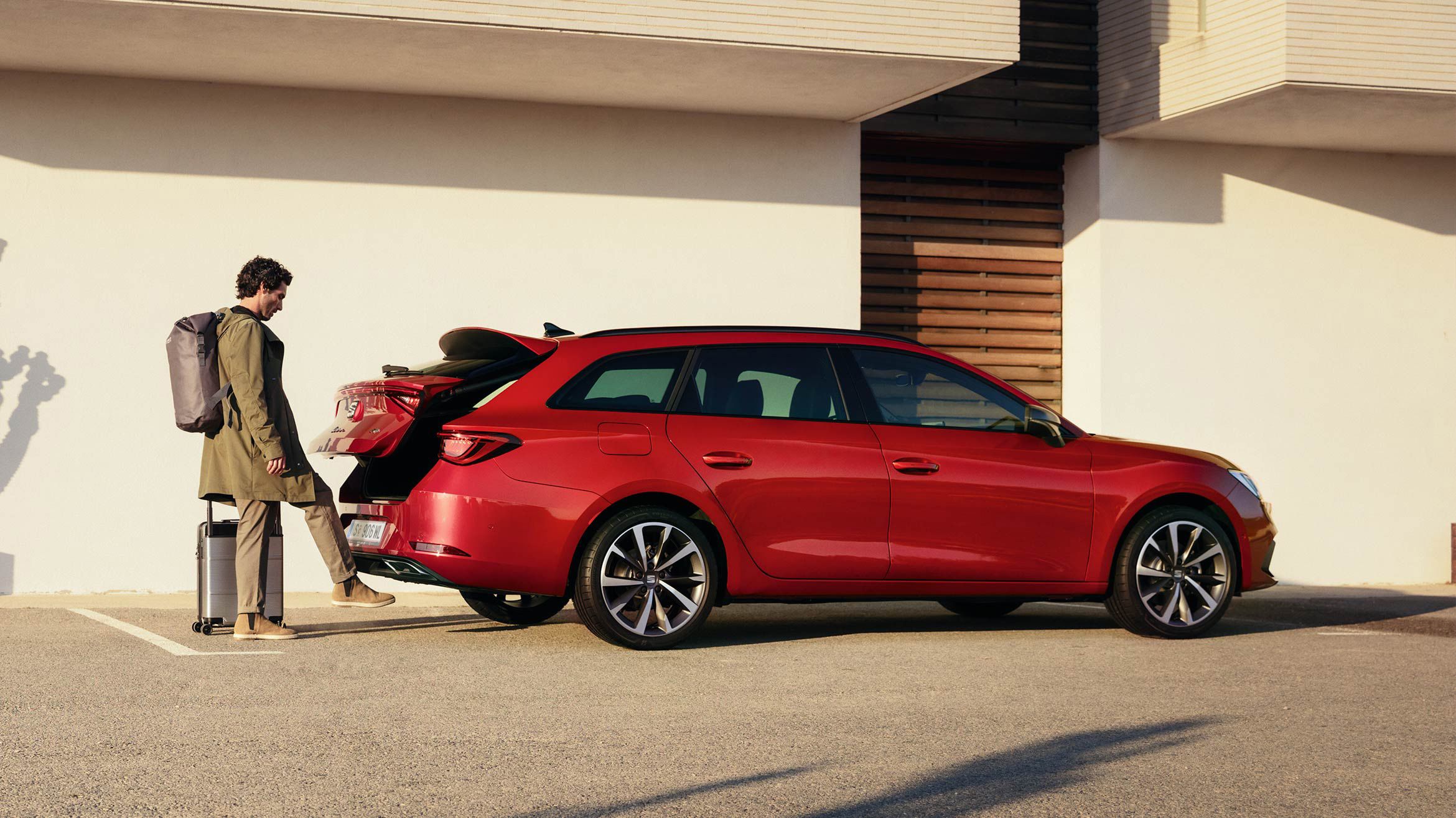 Mann öffnet Kofferraum eines roten SEAT Leon Sportstourer