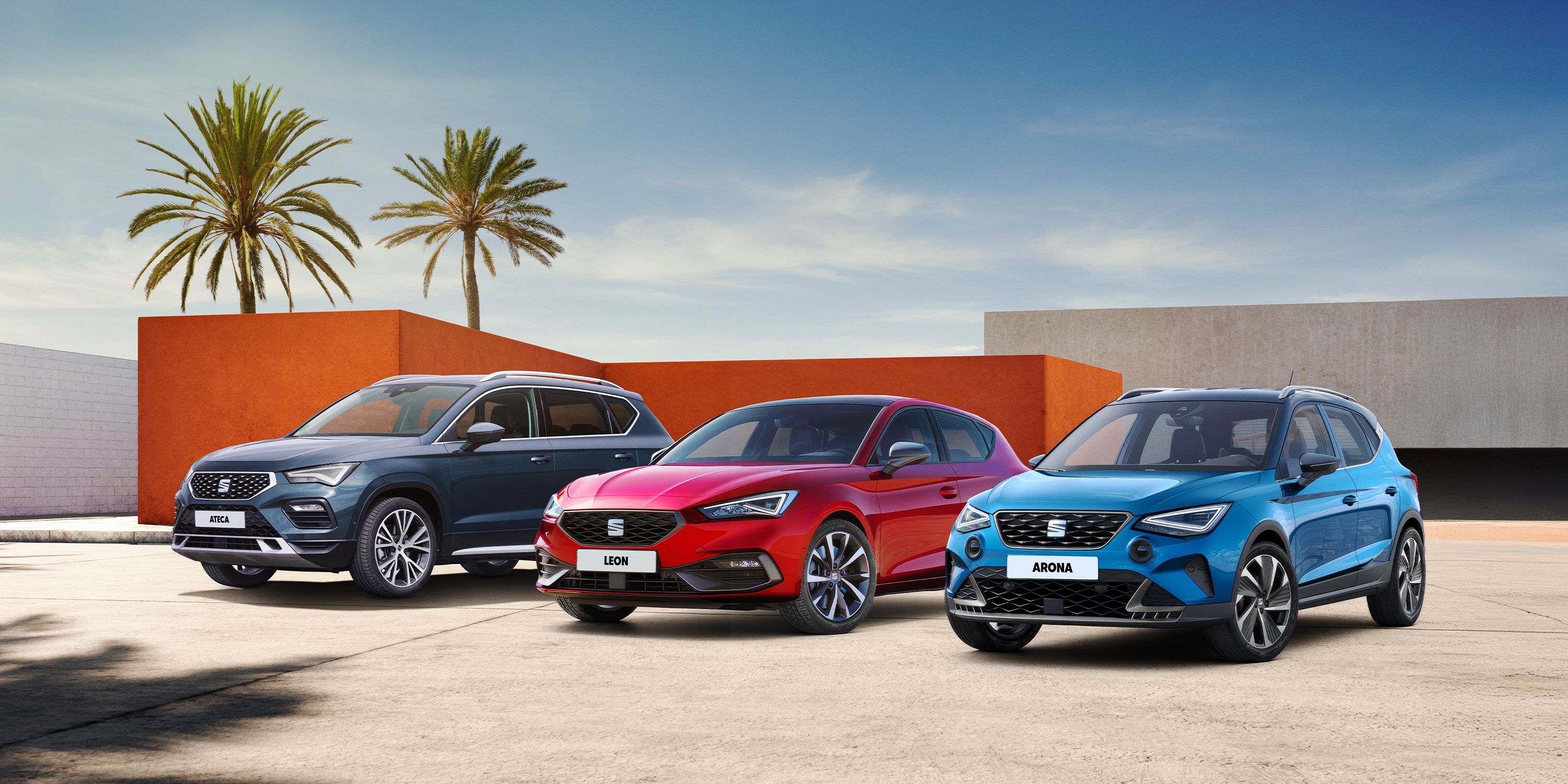 SEAT Arona, Leon a Ateca stoja pred modernou stavbou domu a v pozadí stoja dve palmy.