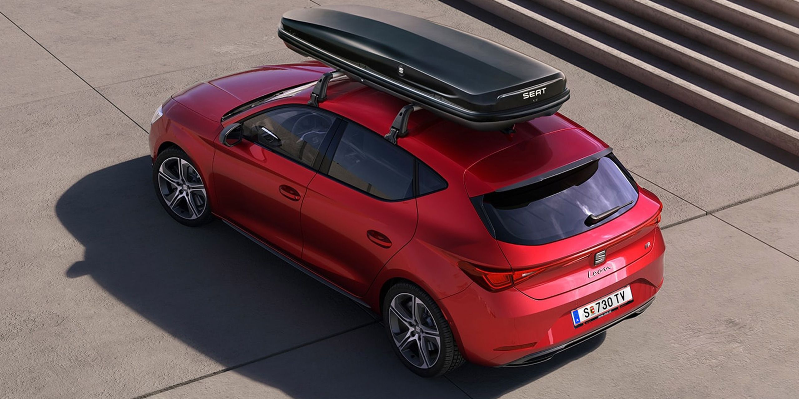 Ein SEAT Leon mit montierten Dachträgern, auf denen eine Dachbox befestigt ist