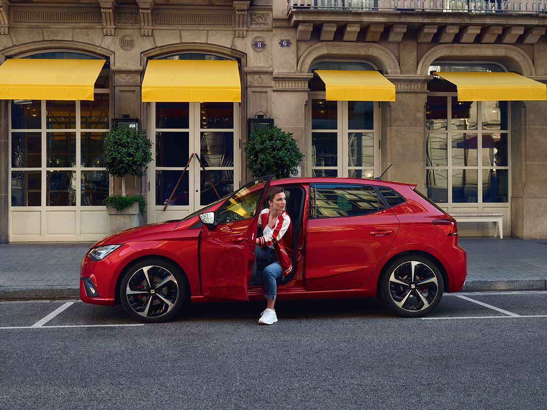Eine Frau steigt aus einem geparkten, roten SEAT Ibiza aus