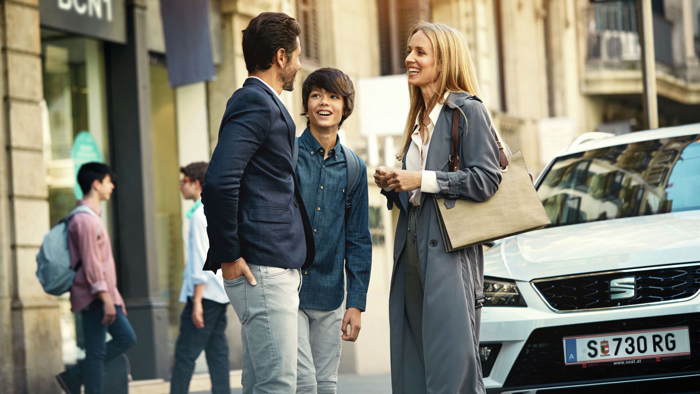 Eine Familie steht vor einem weißen SEAT Ateca 