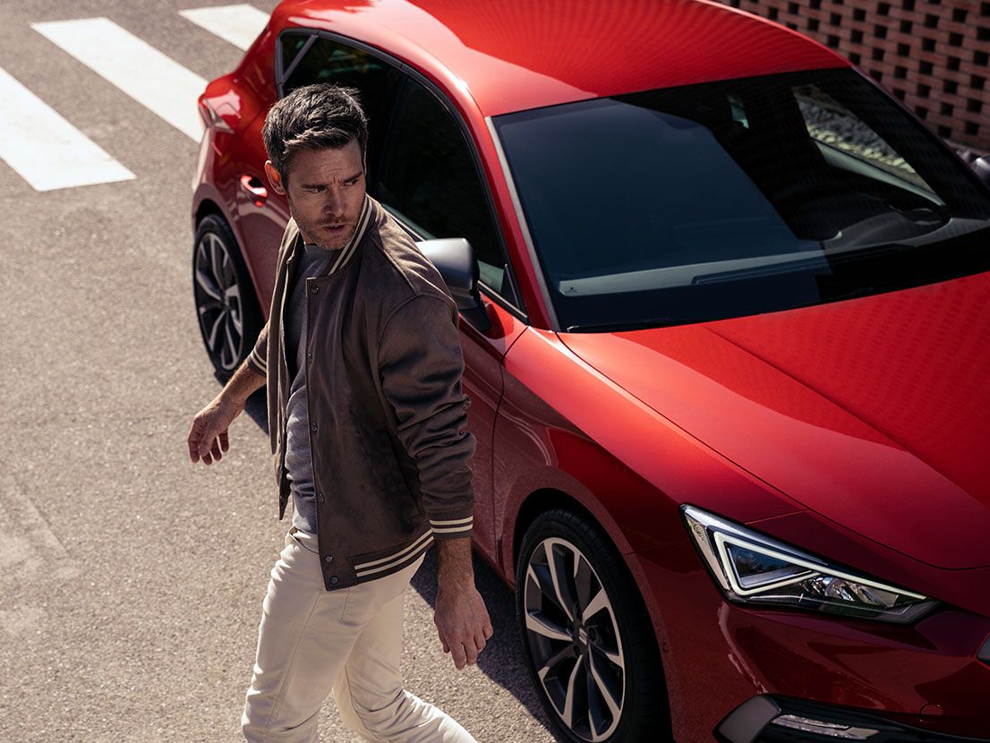 Ein Mann geht vom Sitz weg, im Hintergrund steht ein roter SEAT Leon Desire mit roten Leichtmetallfelgen