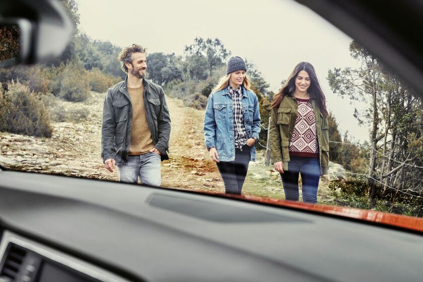 Durch die Windschutzscheibe eines SEAT sieht man zwei Frauen und einen Mann auf das Auto zugehen. 