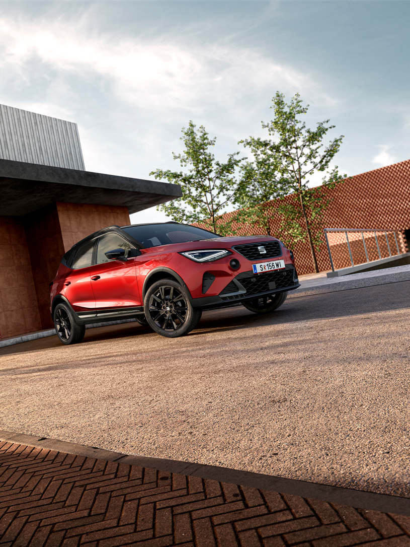 Ein roter SEAT Arona parkt vor einem Gebäude.
