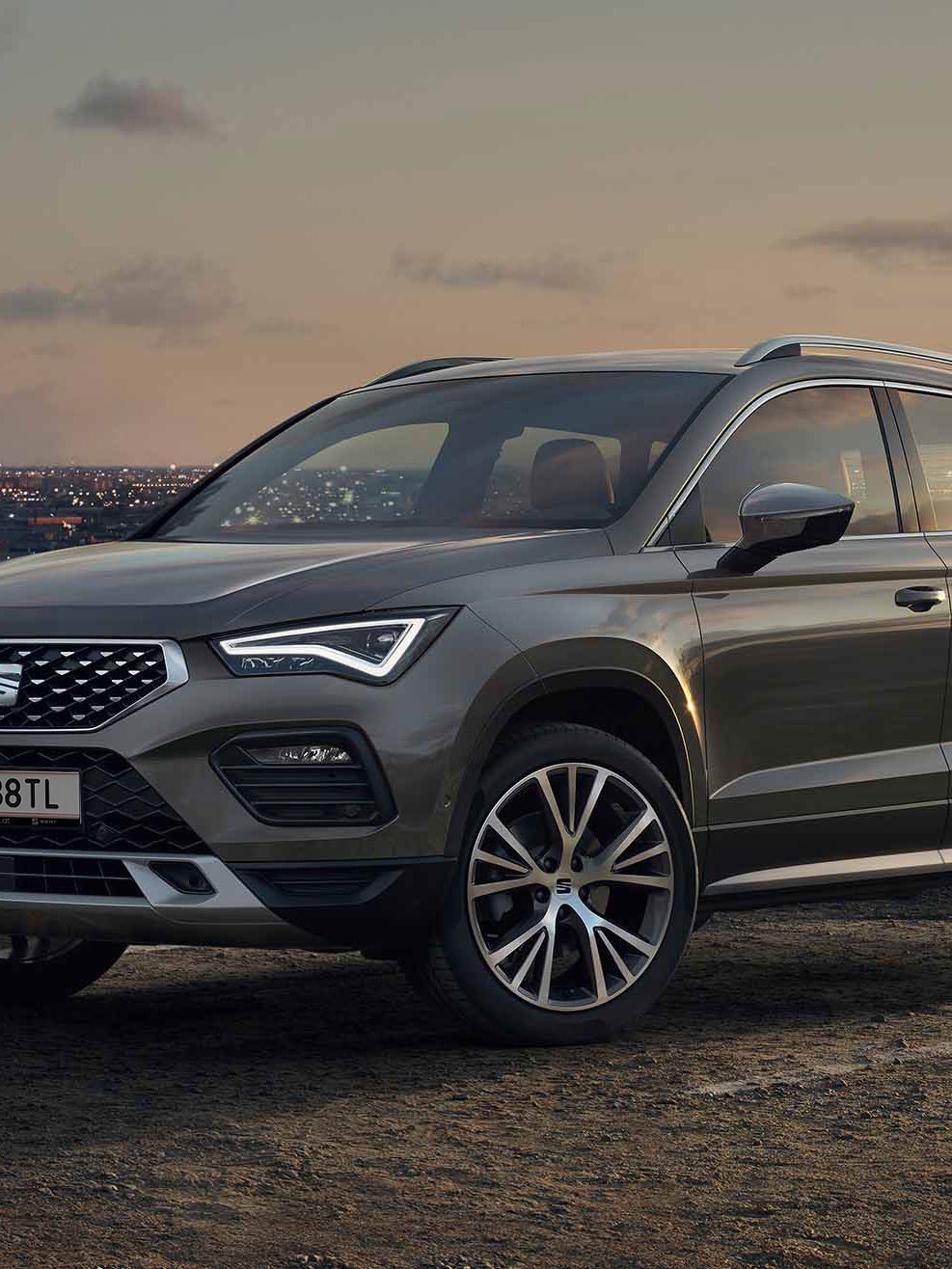 Ein SEAT Ateca SUV in Graphite Grau vor der Skyline einer Stadt im Hintergrund