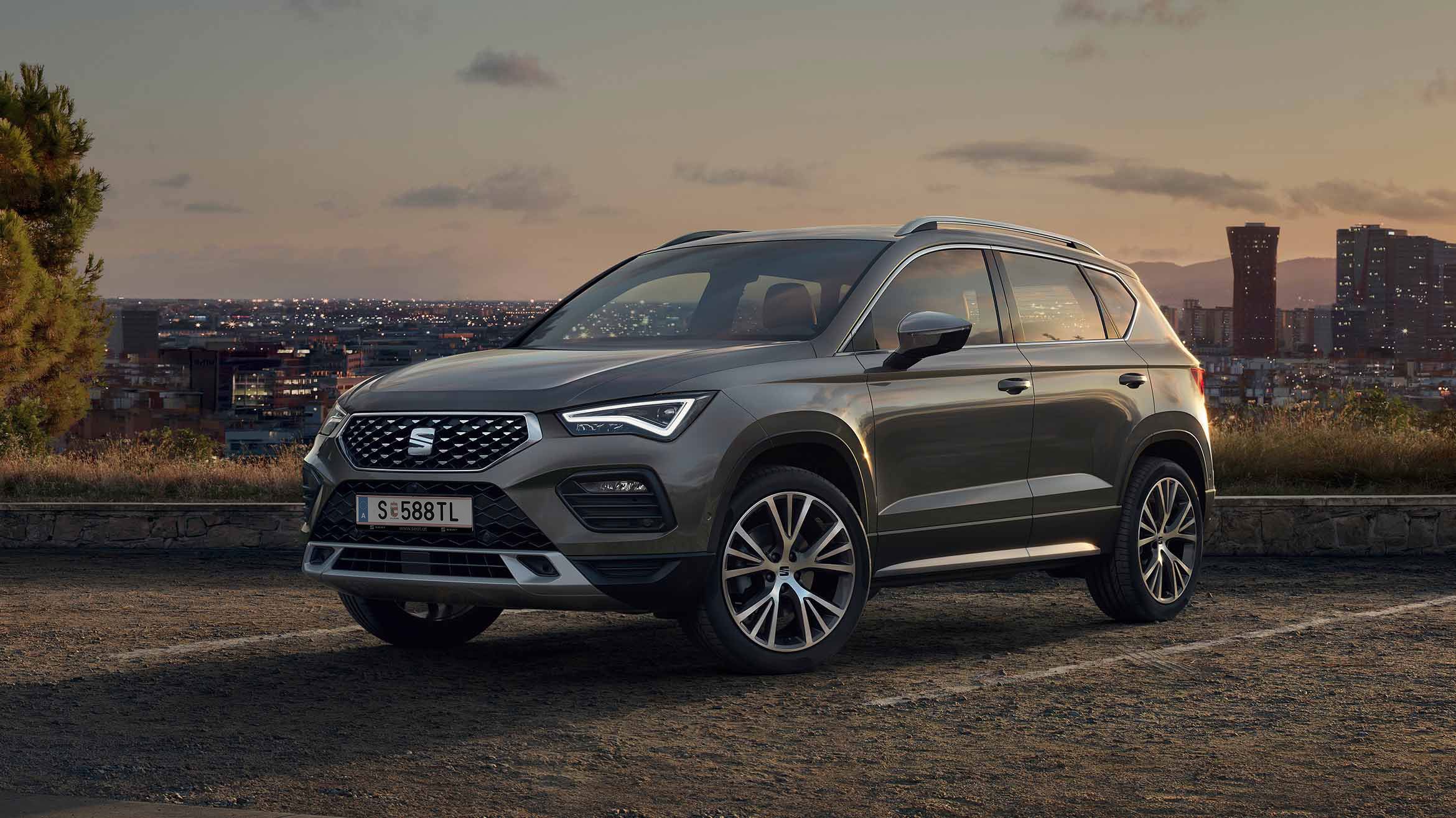 Ein SEAT Ateca SUV in Graphite Grau vor der Skyline einer Stadt im Hintergrund