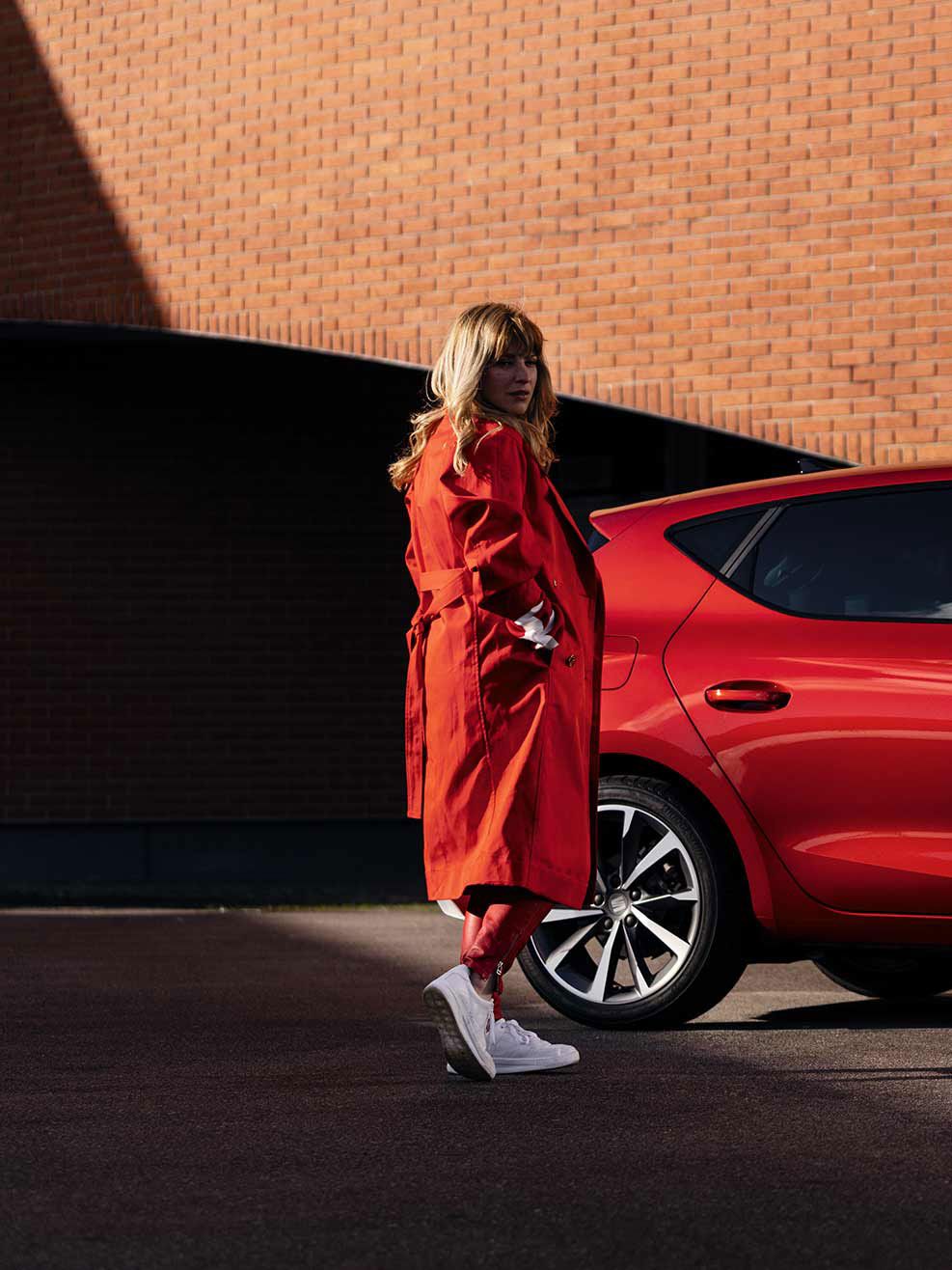 Frau steht neben roten SEAT Leon