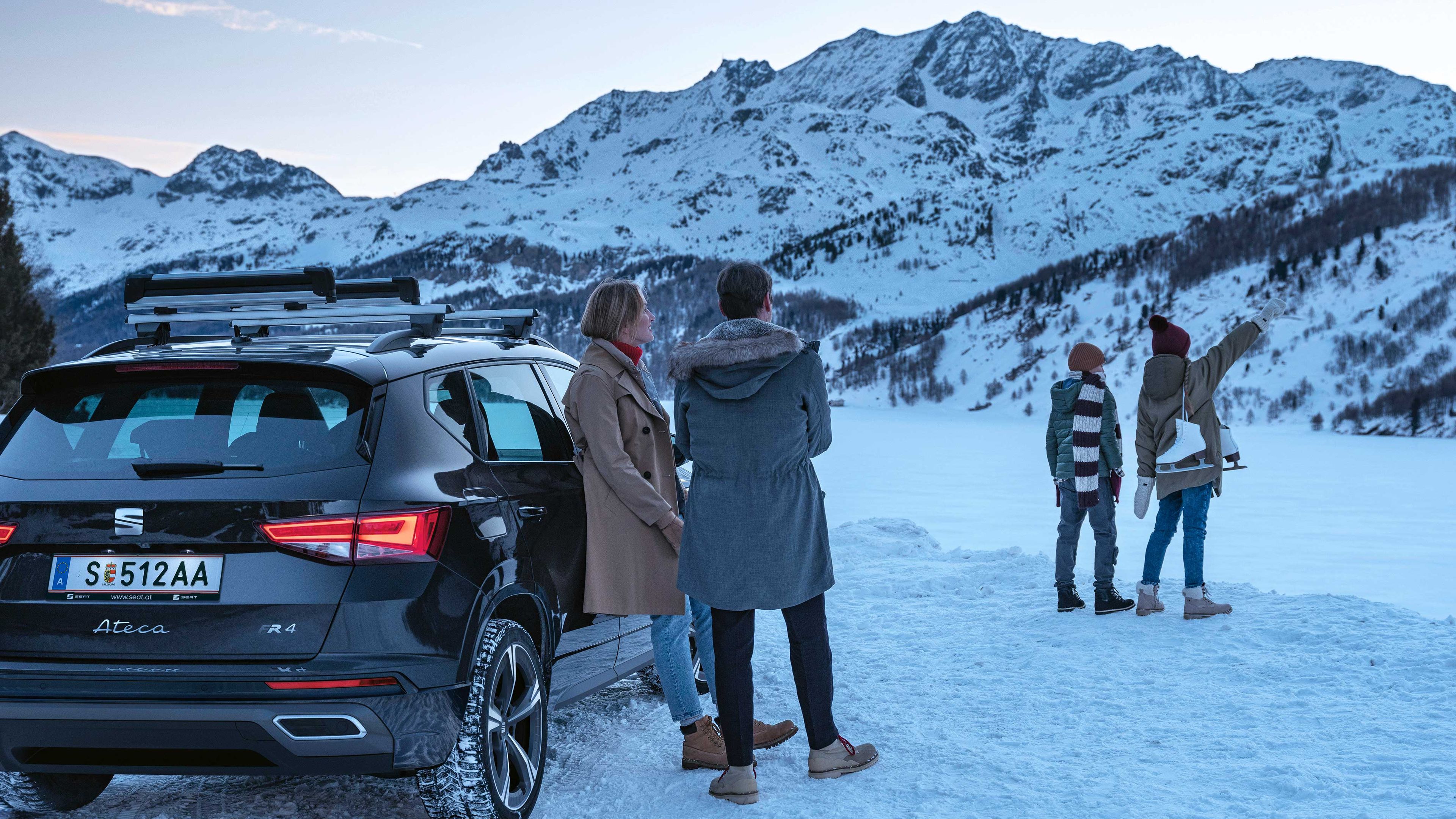 Eine Familie unternimmt einen Winterausflug in die Berge mit ihrem SEAT Ateca und legt nun eine Pause ein