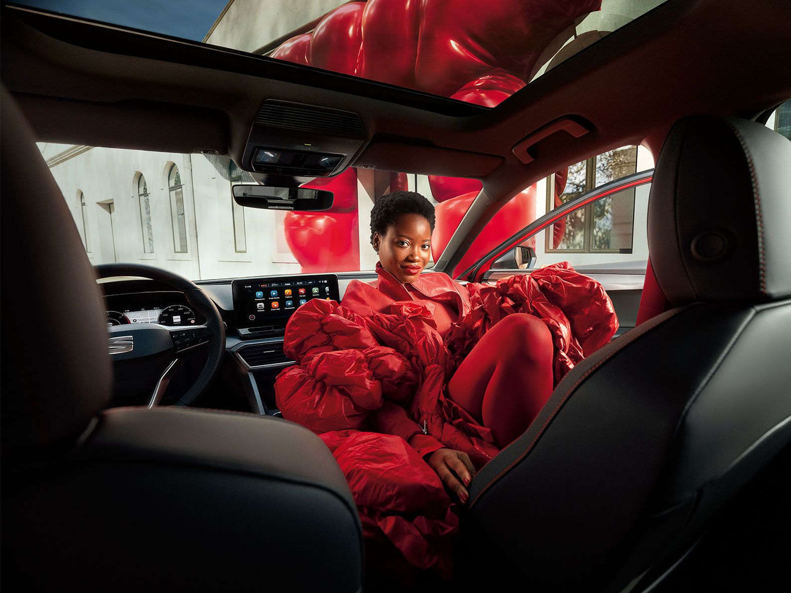 Eine Frau sitzt am Beifahrersitz des SEAT Leon FR, der mit sportlichen Sitzen und Panoramadach ausgestattet ist