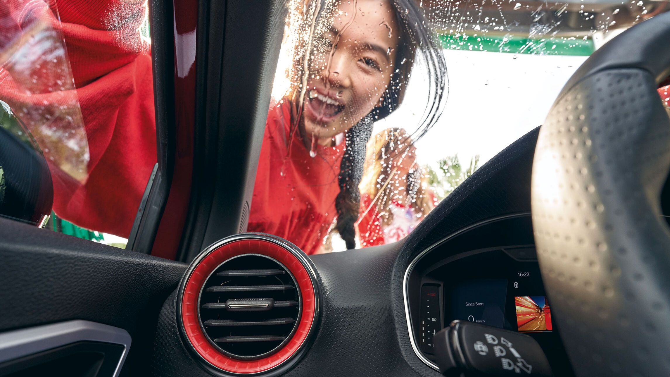 Eine Frau blickt durch die Frontscheibe ins Innere eines SEAT, während sie die Windschutzscheibe wäscht.