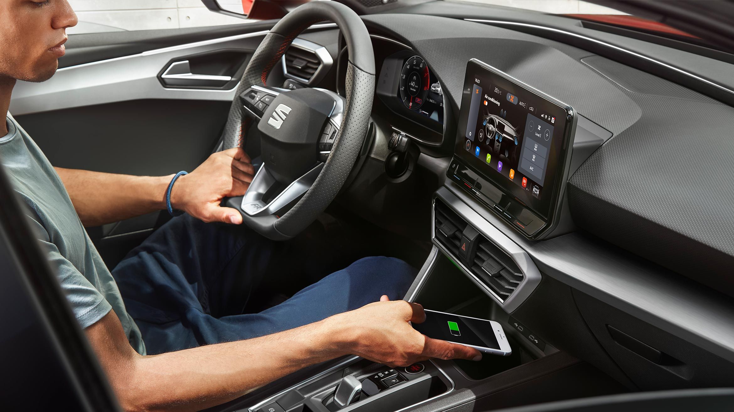 Mann lädt sein Handy auf mit kabellosem Auflade Gerät im SEAT Leon Sportstourer