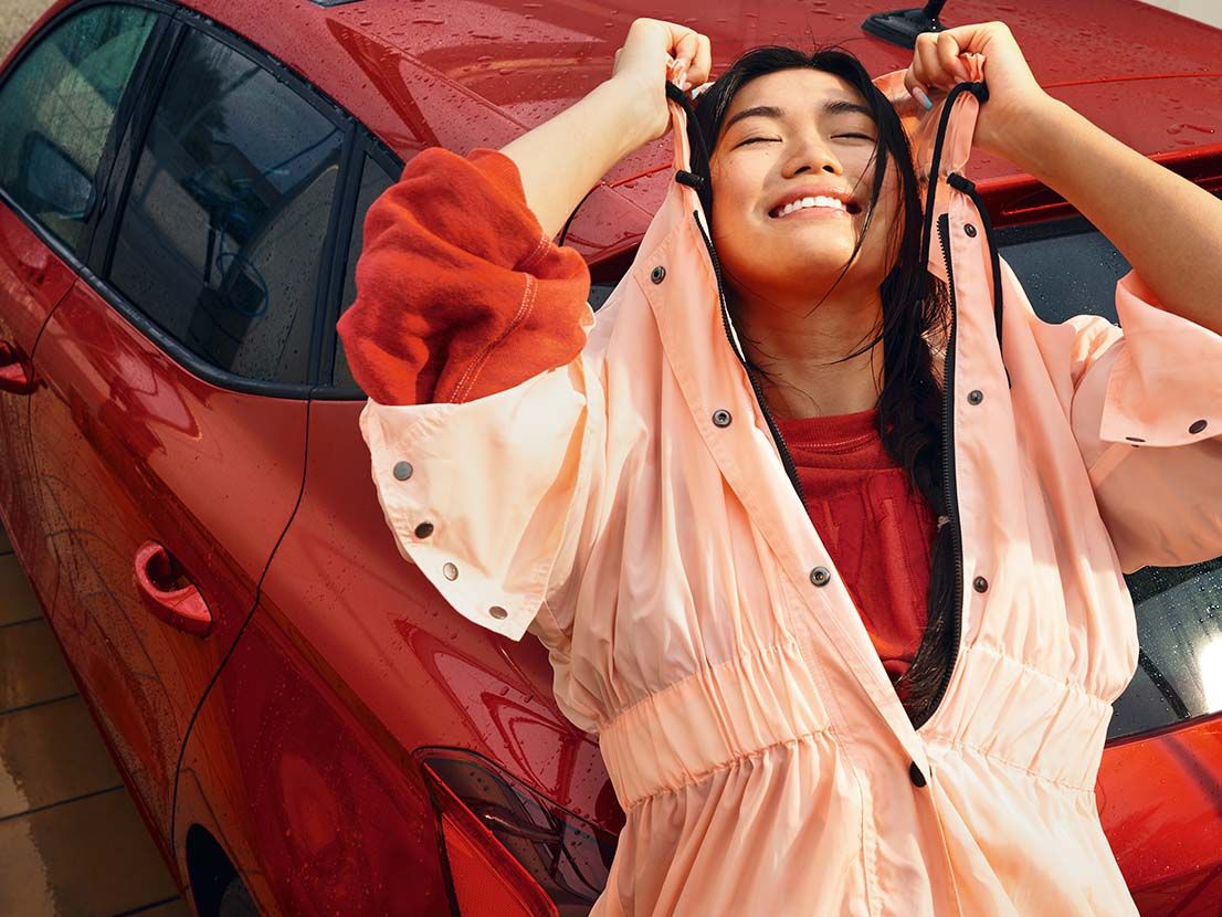 Eine lächelnde Frau lehnt an einem roten SEAT Ibiza