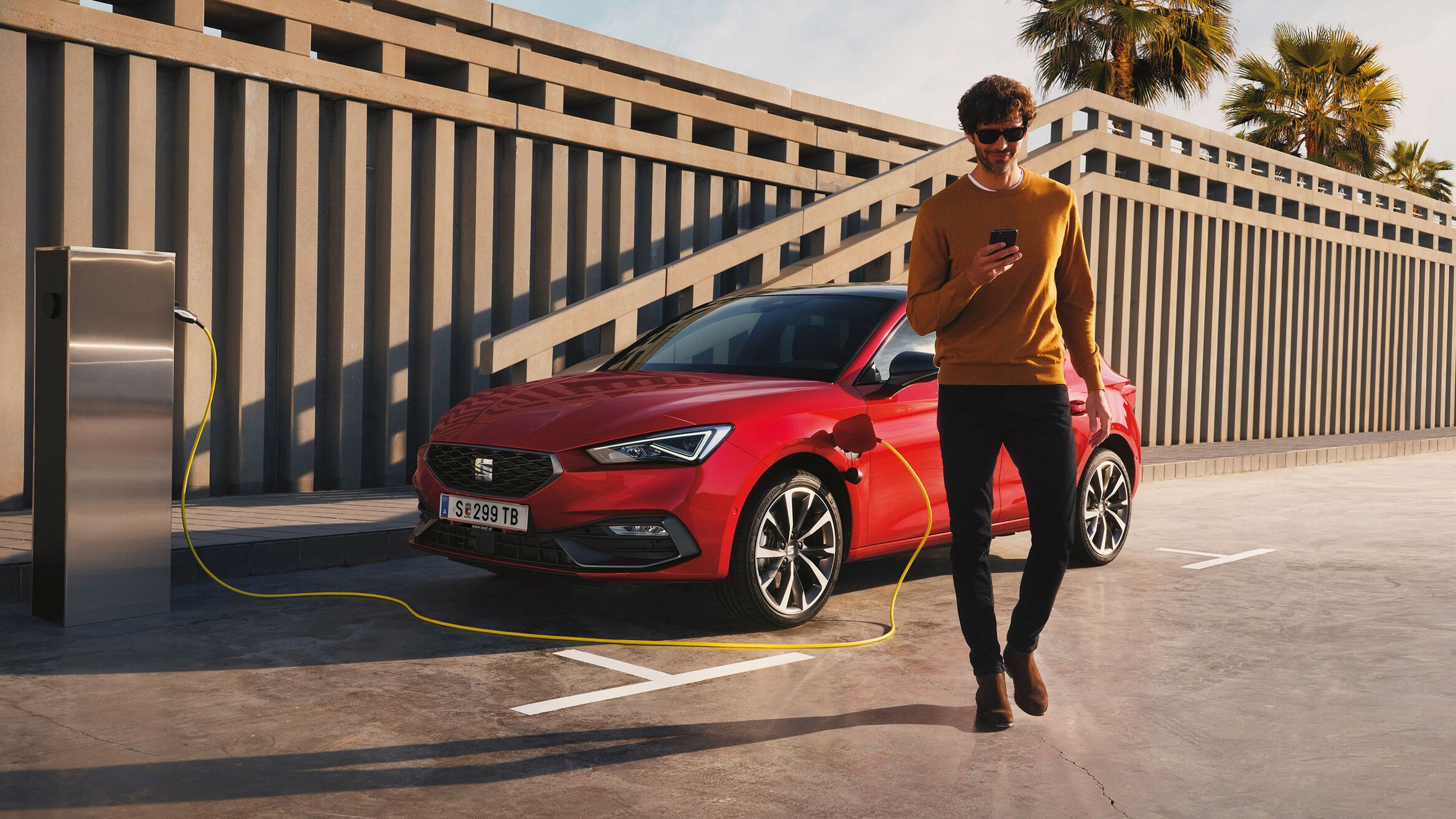 Ein roter SEAT Ibiza steht an der Ladesäule. Ein Mann geht neben dem Auto.