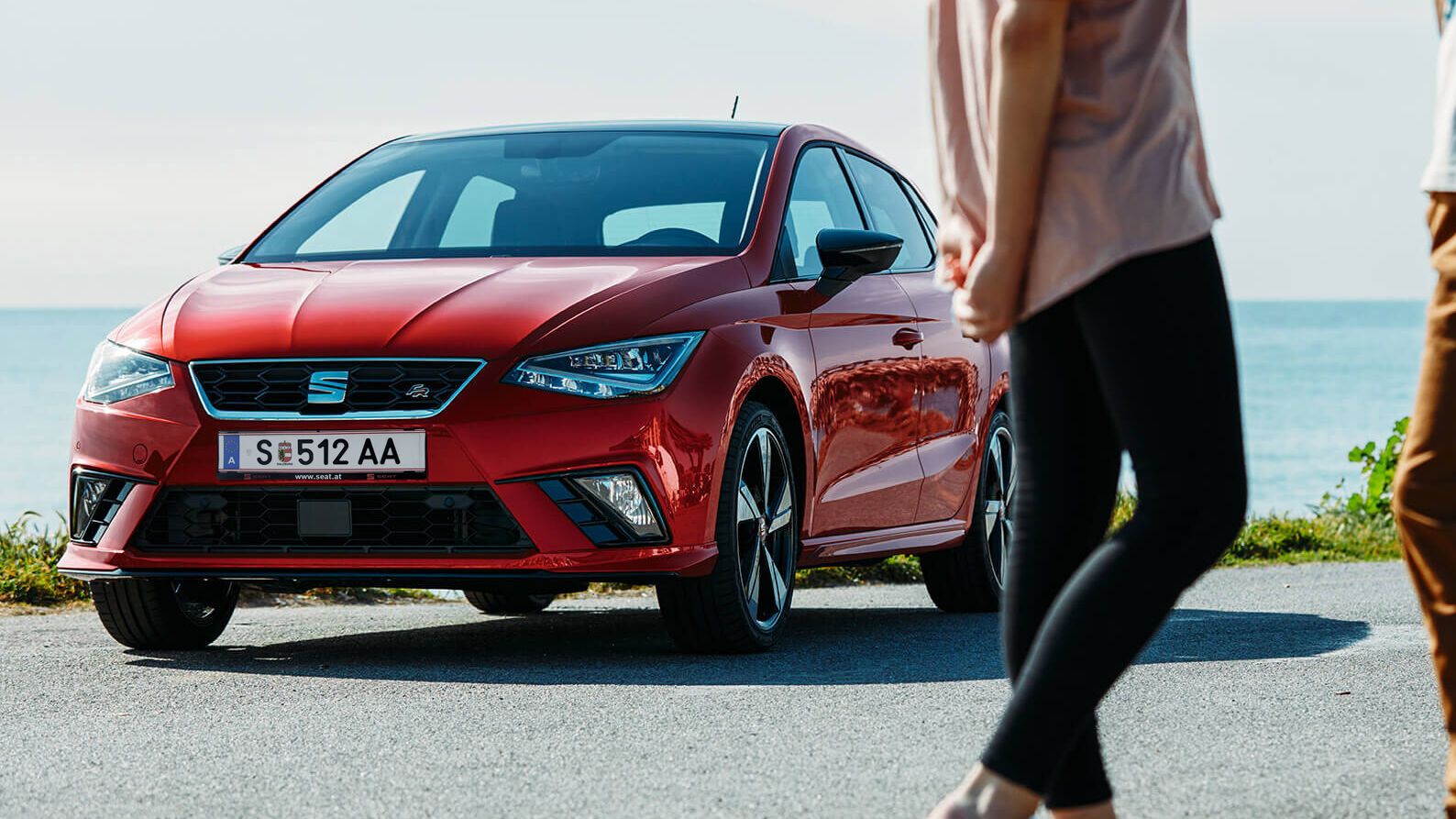 SEAT Ibiza FR steht auf einer Küstenstraße. Im Vordergrund sind zwei Männer. 