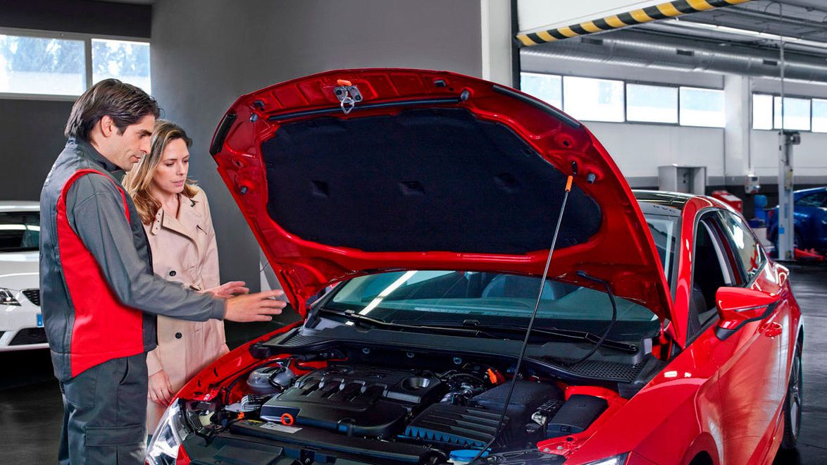 Zu sehen ist ein SEAT Mechaniker und eine Frau vor einer geöffneten Motorhaube.