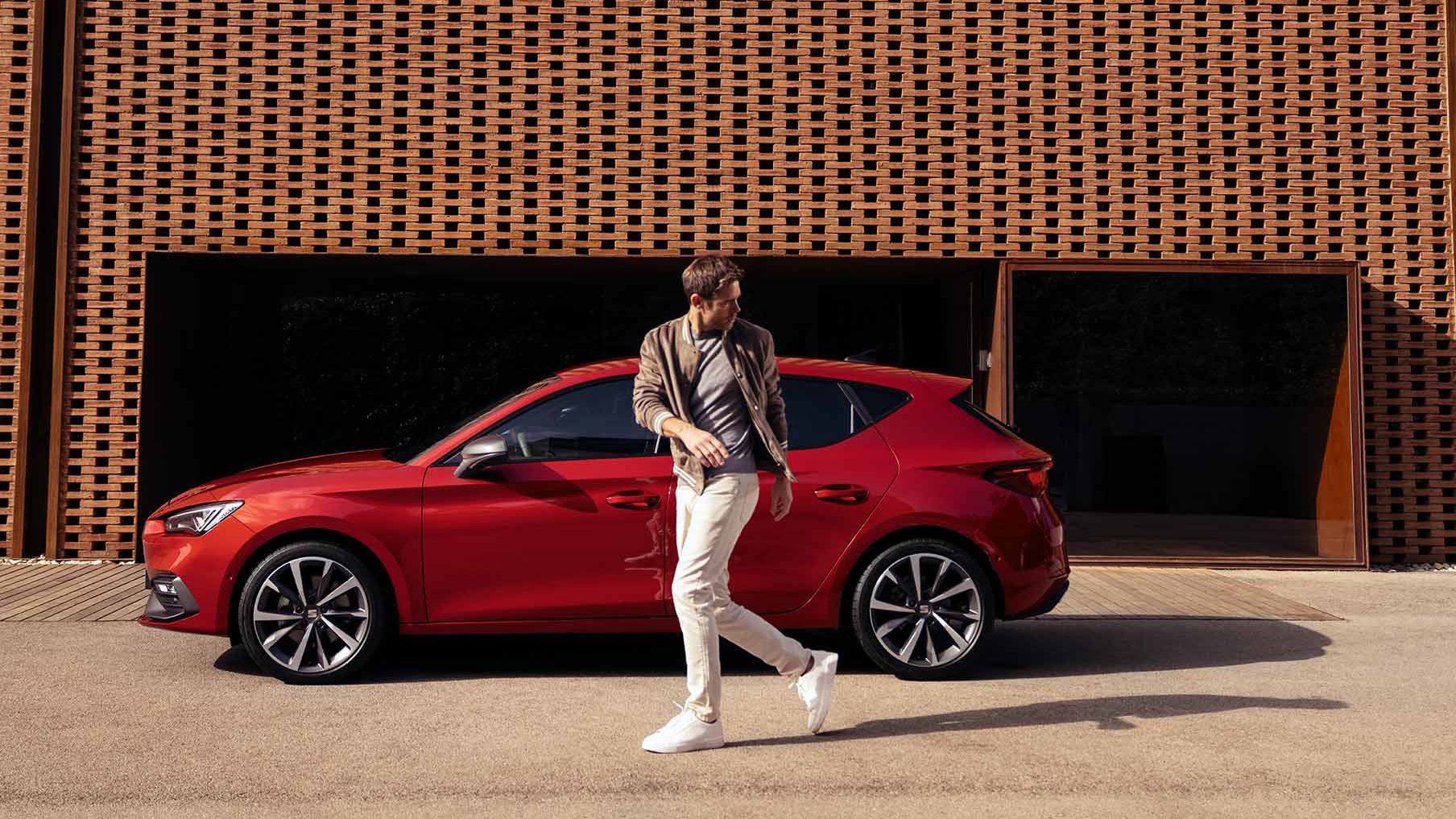 Mann geht an roten SEAT Leon vorbei