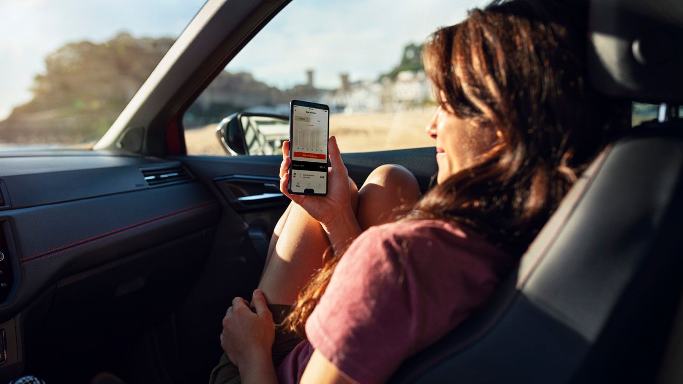 Eine Frau auf dem Beifahrersitz blickt auf ihr Smartphone-Imagebild SEAT