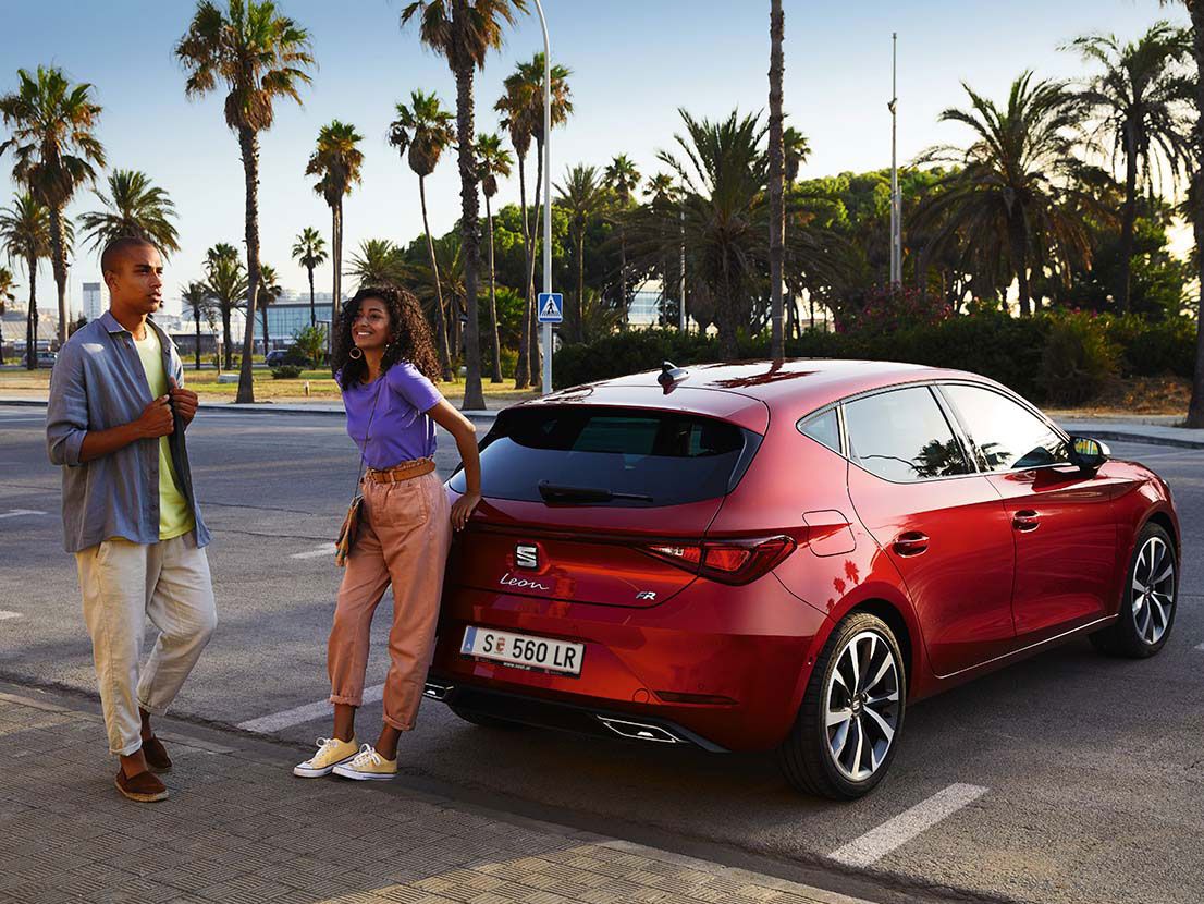 Casal a conversar junto ao SEAT Leon vermelho desire