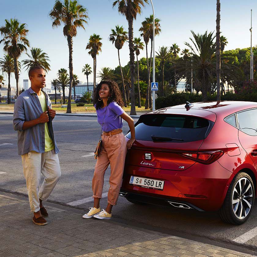 Casal a conversar junto ao SEAT Leon vermelho desire