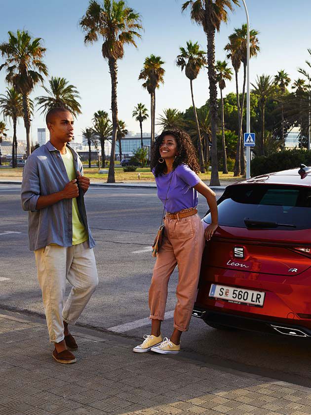 Casal a conversar junto ao SEAT Leon vermelho desire