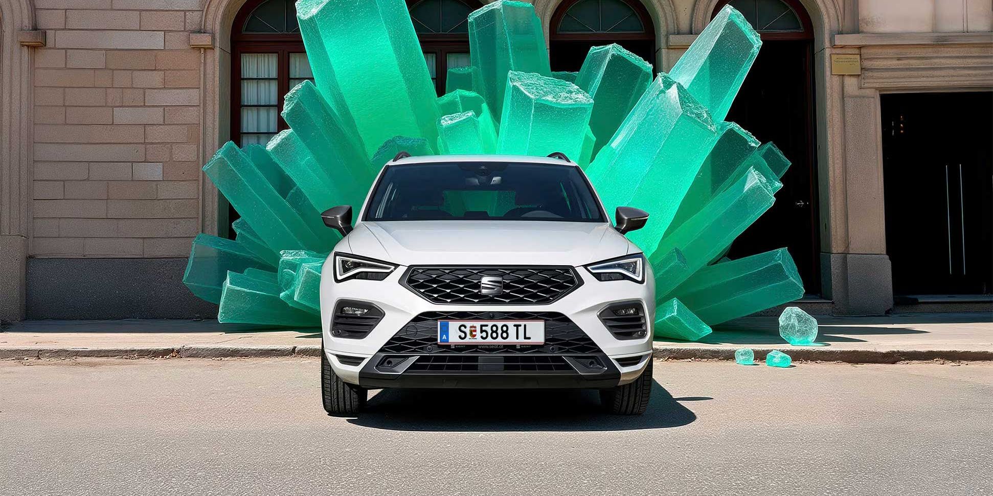 Ein weißer SEAT Ateca steht vor einem Gebäude, hinter dem Fahrzeug sind grüne Kristalle.