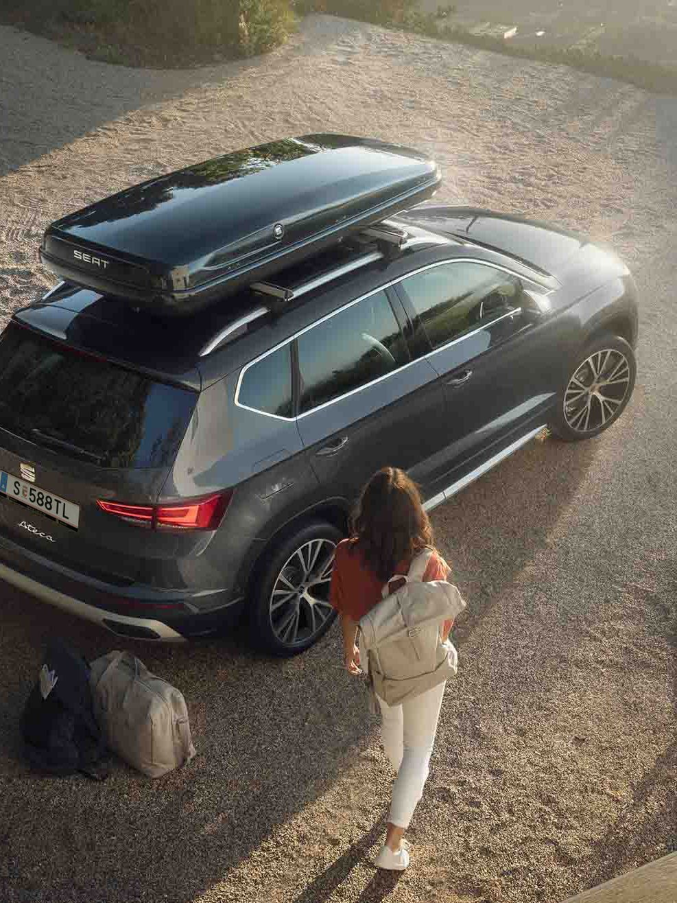 Ein graphitegrauer SEAT Ateca mit Dachbox – ein Paar packt ein und macht sich bereit für den nächsten Trip
