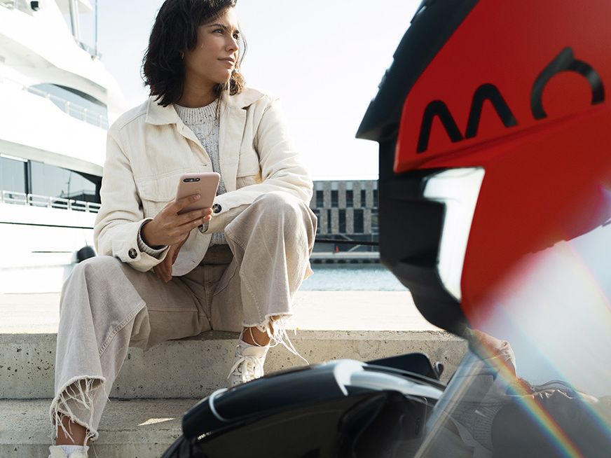 mulher sentada junto da scooter elétrica SEAT MÓ 125 