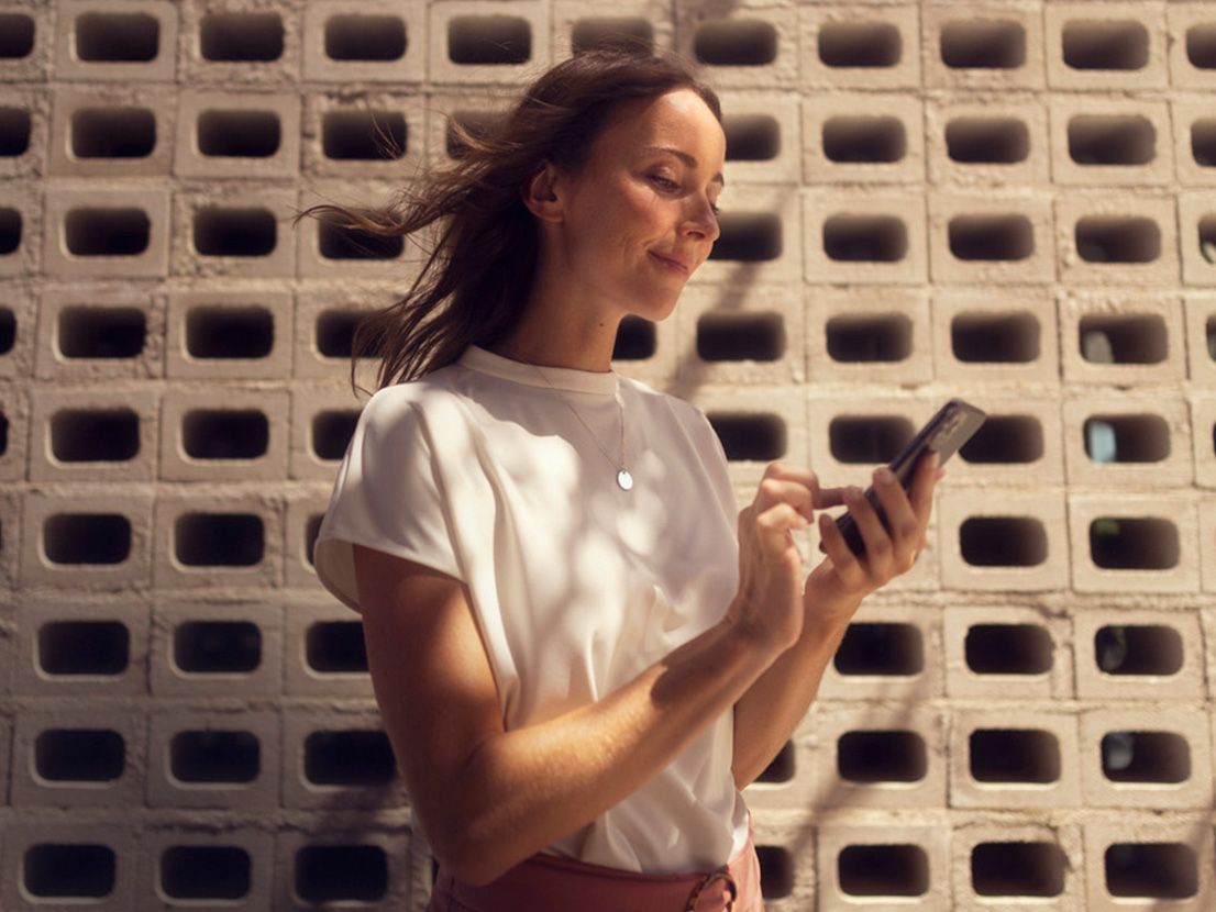 Eine Frau hält ihr Smartphone in der Hand und verwendet SEAT Connect
